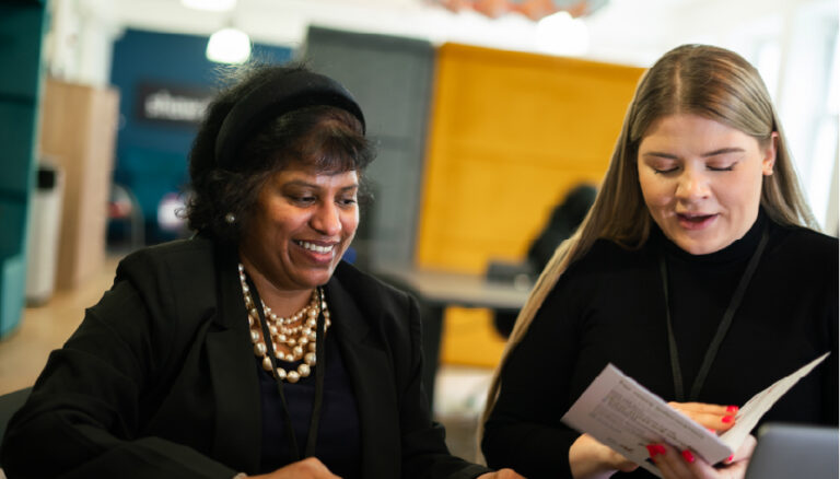 Lady sits reading with another lady