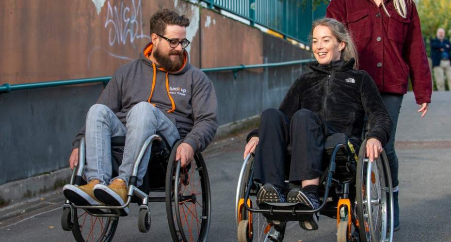 Two people in wheel chairs smiling